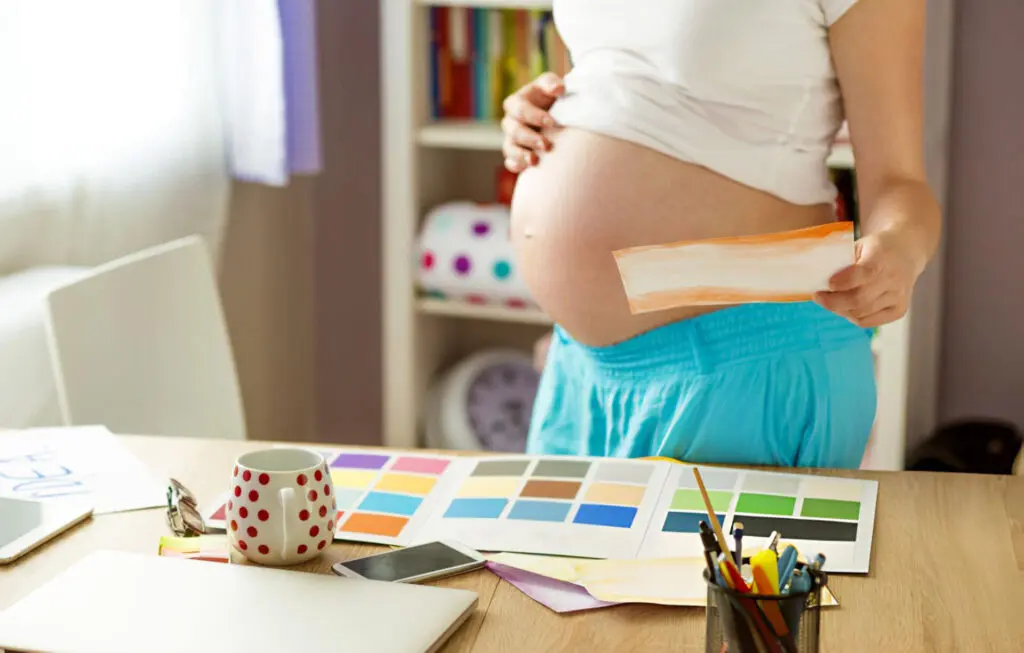 pregnant woman holding a paper with color palette on table