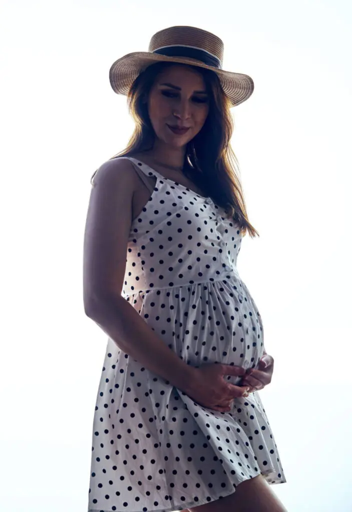 a pregnant woman wearing a hat and dress