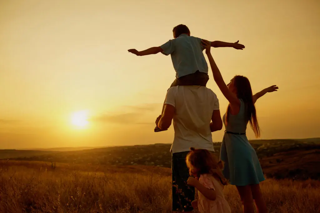 a family with a child on their shoulders in a field