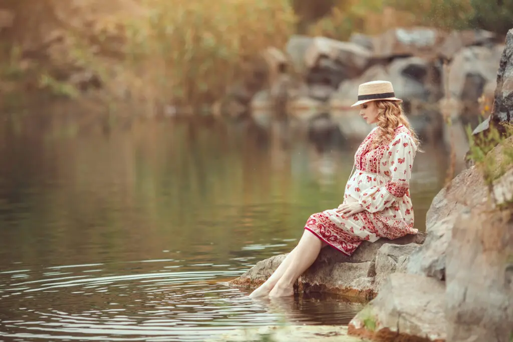 a woman sitting on a rock in water
